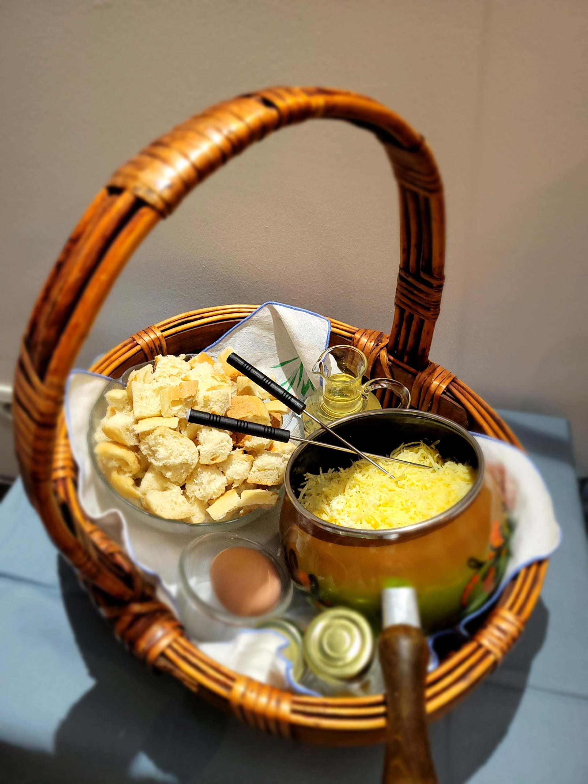 20240221_193113 Panier en osier avec fromage, pain et ingrédients pour une fondue savoureuse.
