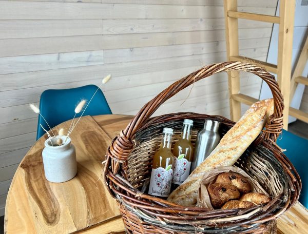 Panier gourmand dans un gîte cosy, avec pains et boissons artisanales.
