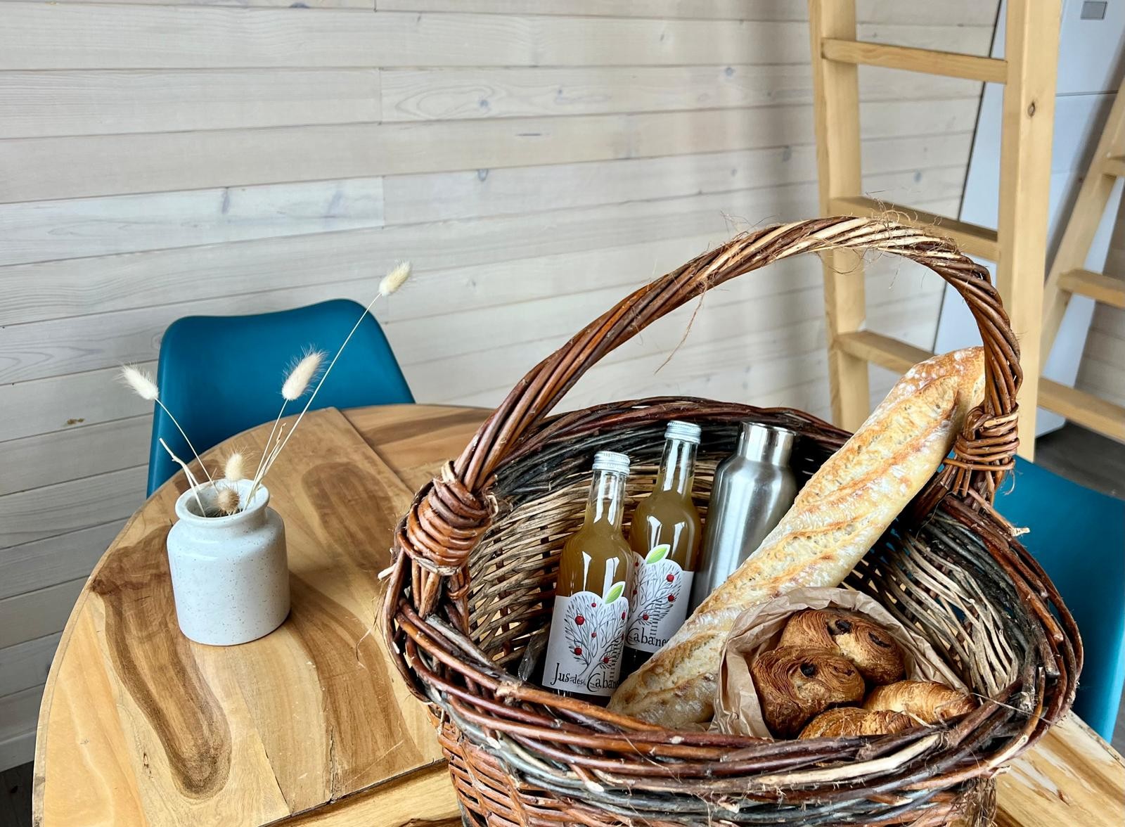Panier gourmand dans un gîte cosy, avec pains et boissons artisanales.