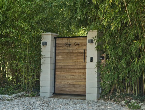 Entrée dune villa moderne entourée de bambous luxuriants et dun chemin en gravier.