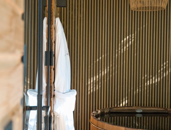 Cabane en bois avec un bain nordique et des peignoirs suspendus.