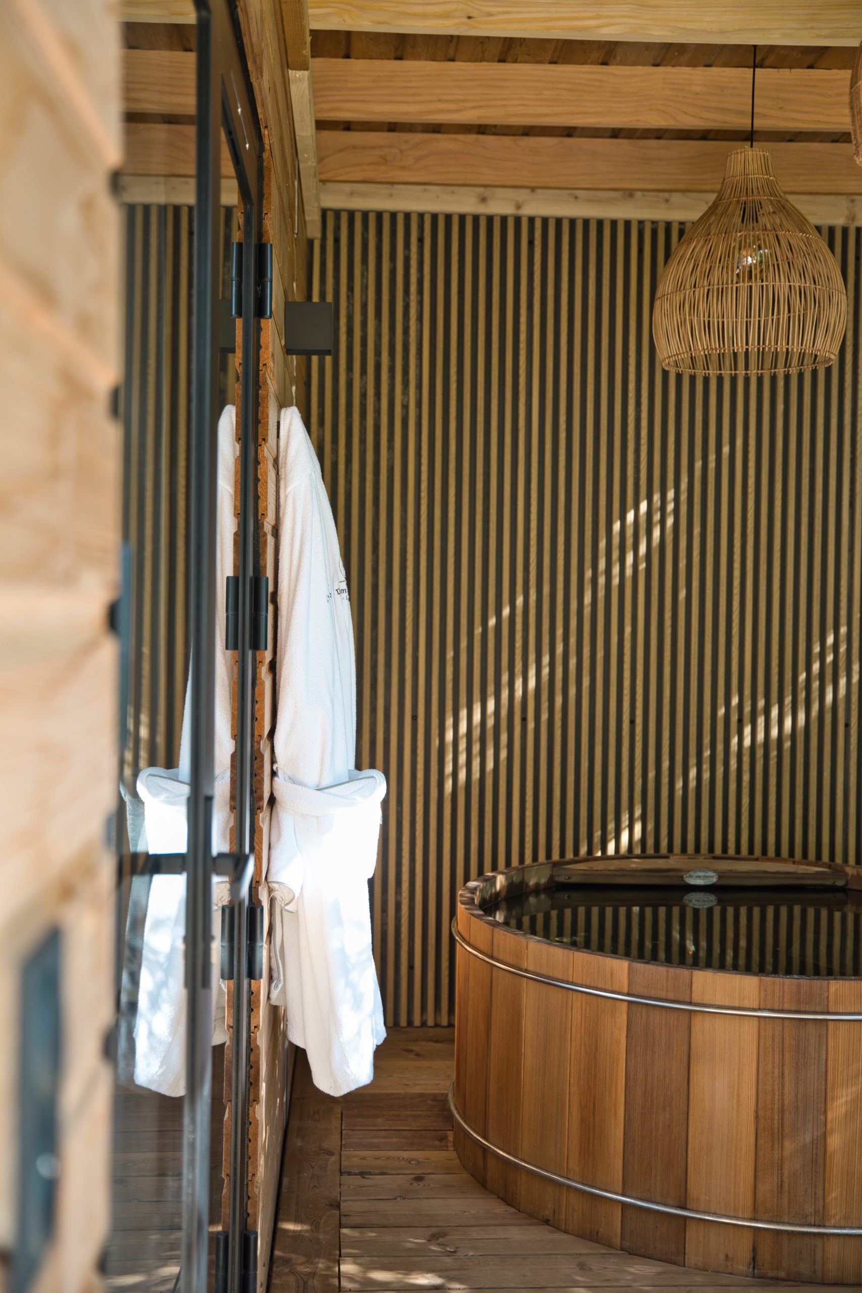Cabane en bois avec un bain nordique et des peignoirs suspendus.