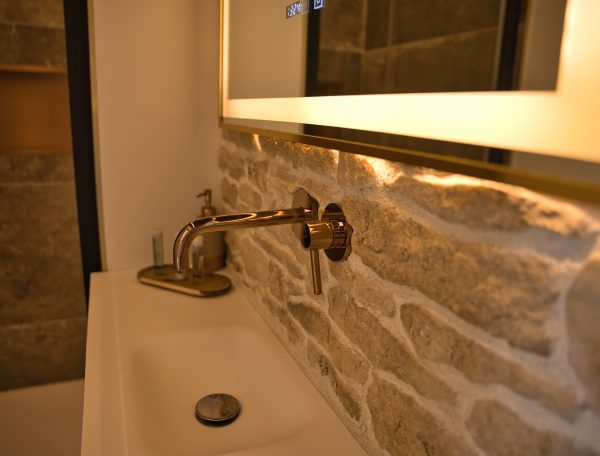 Salle de bain moderne dans un hébergement touristique, avec un lavabo en pierre et un éclairage