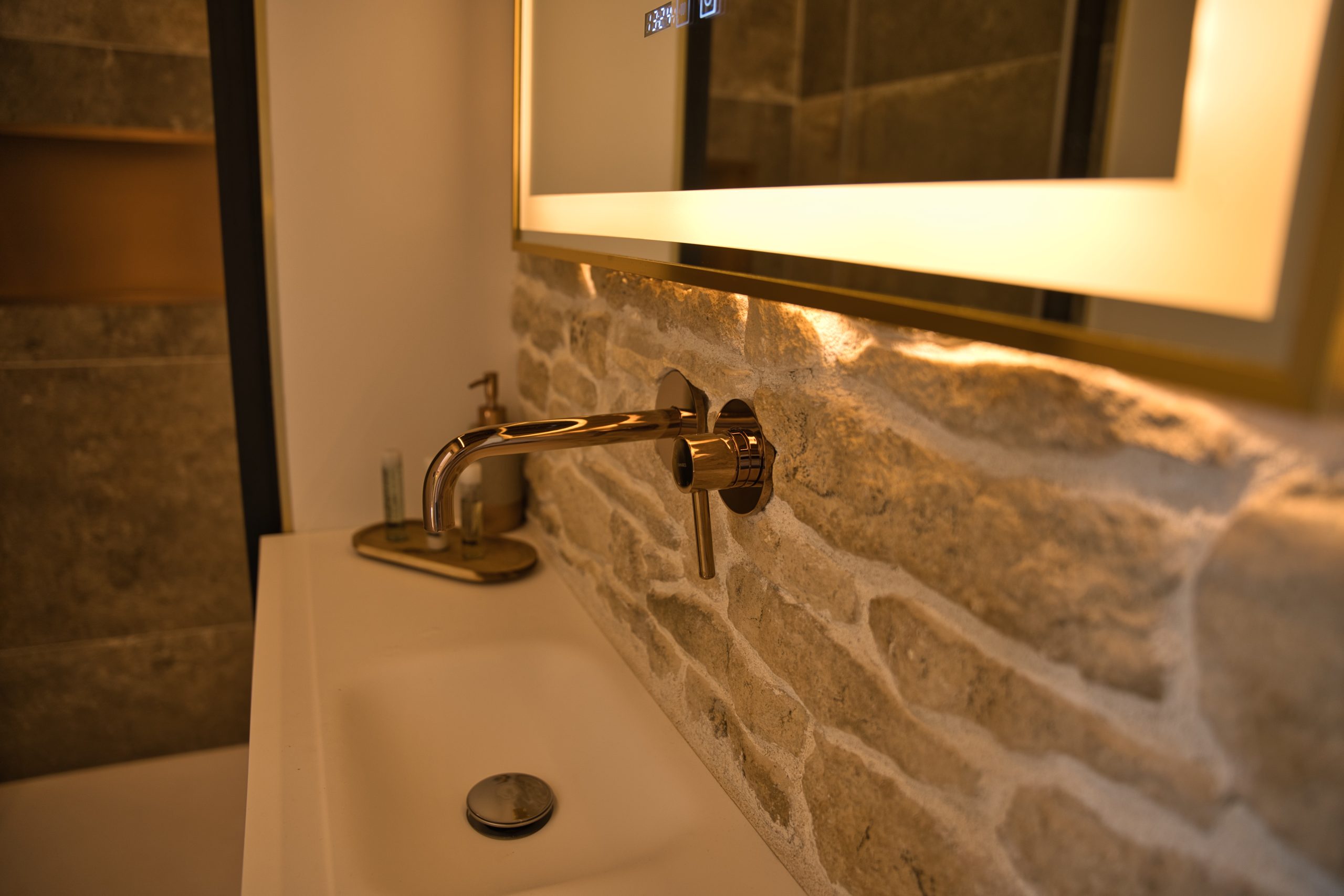 Salle de bain moderne dans un hébergement touristique, avec un lavabo en pierre et un éclairage