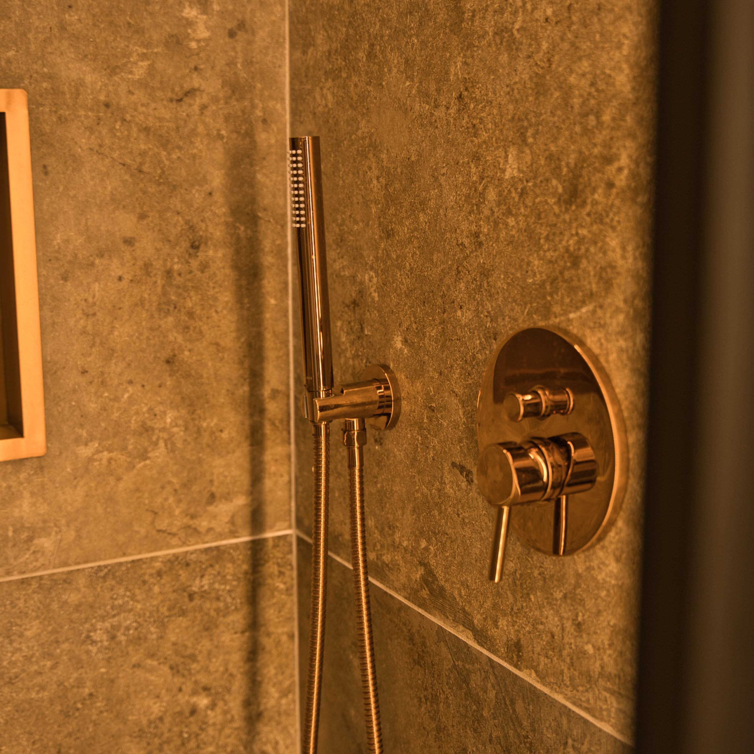 Salle de bain moderne avec douche en marbre et robinetterie dorée élégante.
