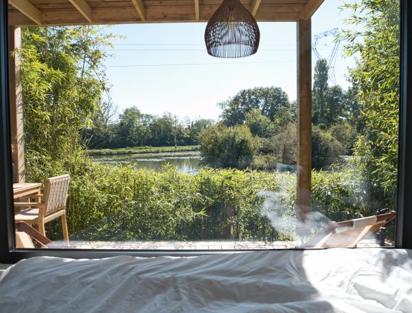 Chalet moderne avec vue sur un étang, entouré de verdure apaisante.