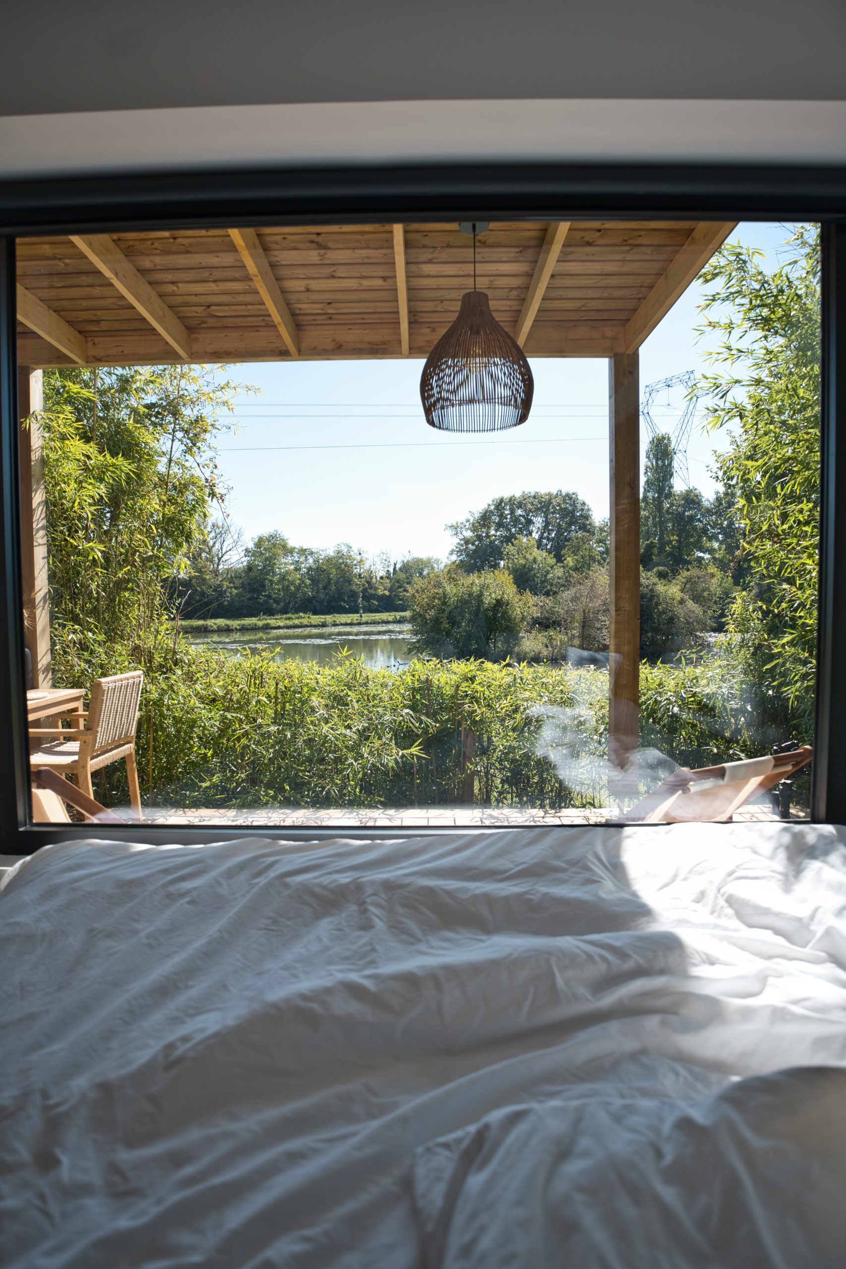 Chalet moderne avec vue sur un étang, entouré de verdure apaisante.