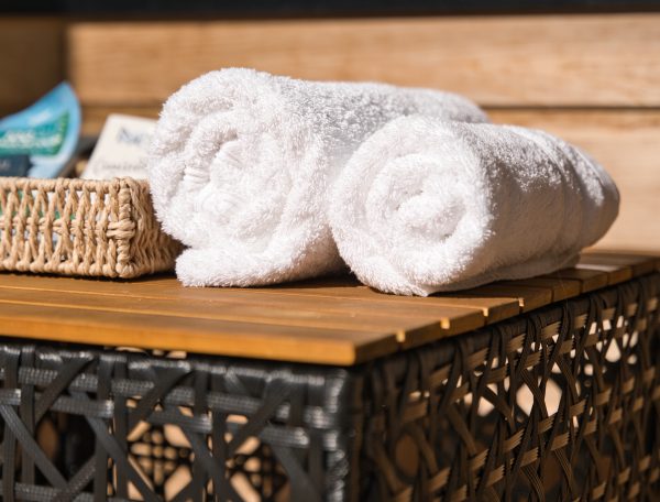 Hébergement de luxe avec serviettes blanches soigneusement enroulées sur une table en osier.