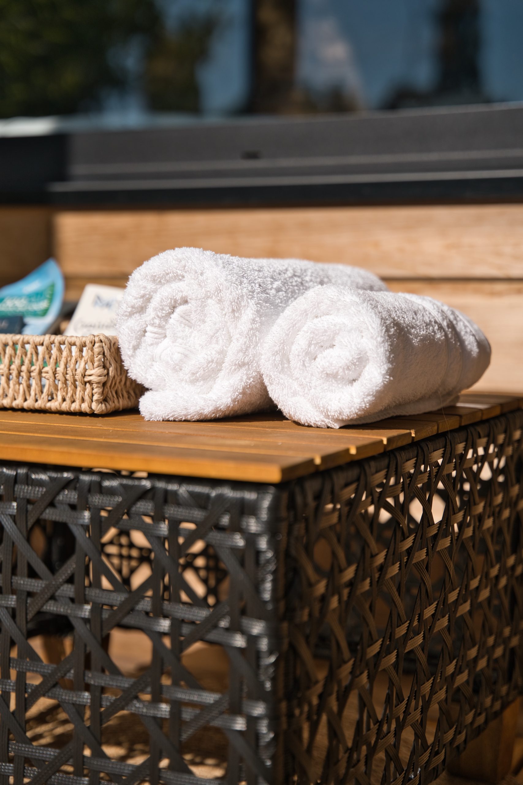 Hébergement de luxe avec serviettes blanches soigneusement enroulées sur une table en osier.