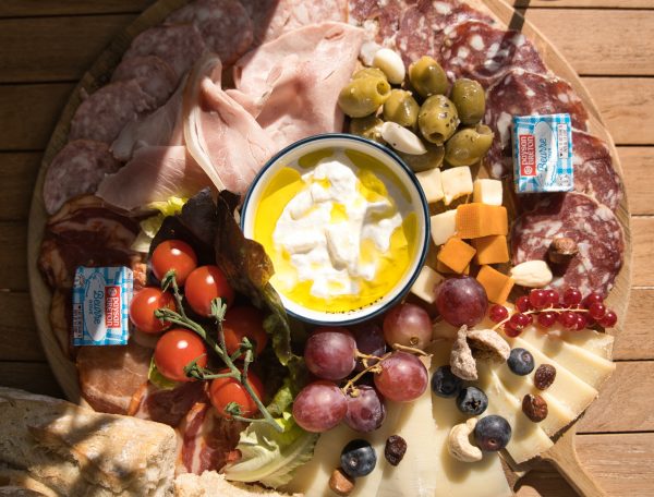 Plateau de charcuterie dans un gîte, avec fromages, olives et tomates cerises.