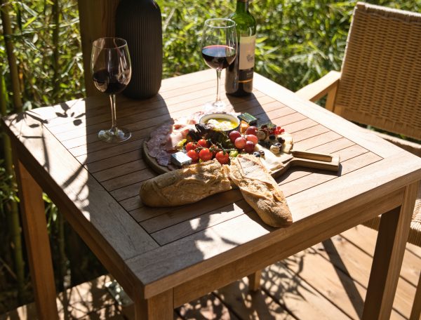 Table en bois avec un repas gourmet et vin, vue sur la rivière. Idéal pour un séjour romantique.