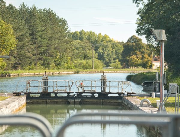 Écluse paisible au bord dun canal, entourée de verdure et de nature.