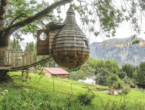 Cabane dans les arbres avec vue sur les montagnes et la nature environnante.