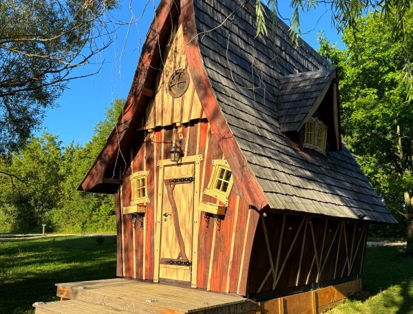 Charmante cabane en bois avec un toit pentu et des fenêtres colorées.