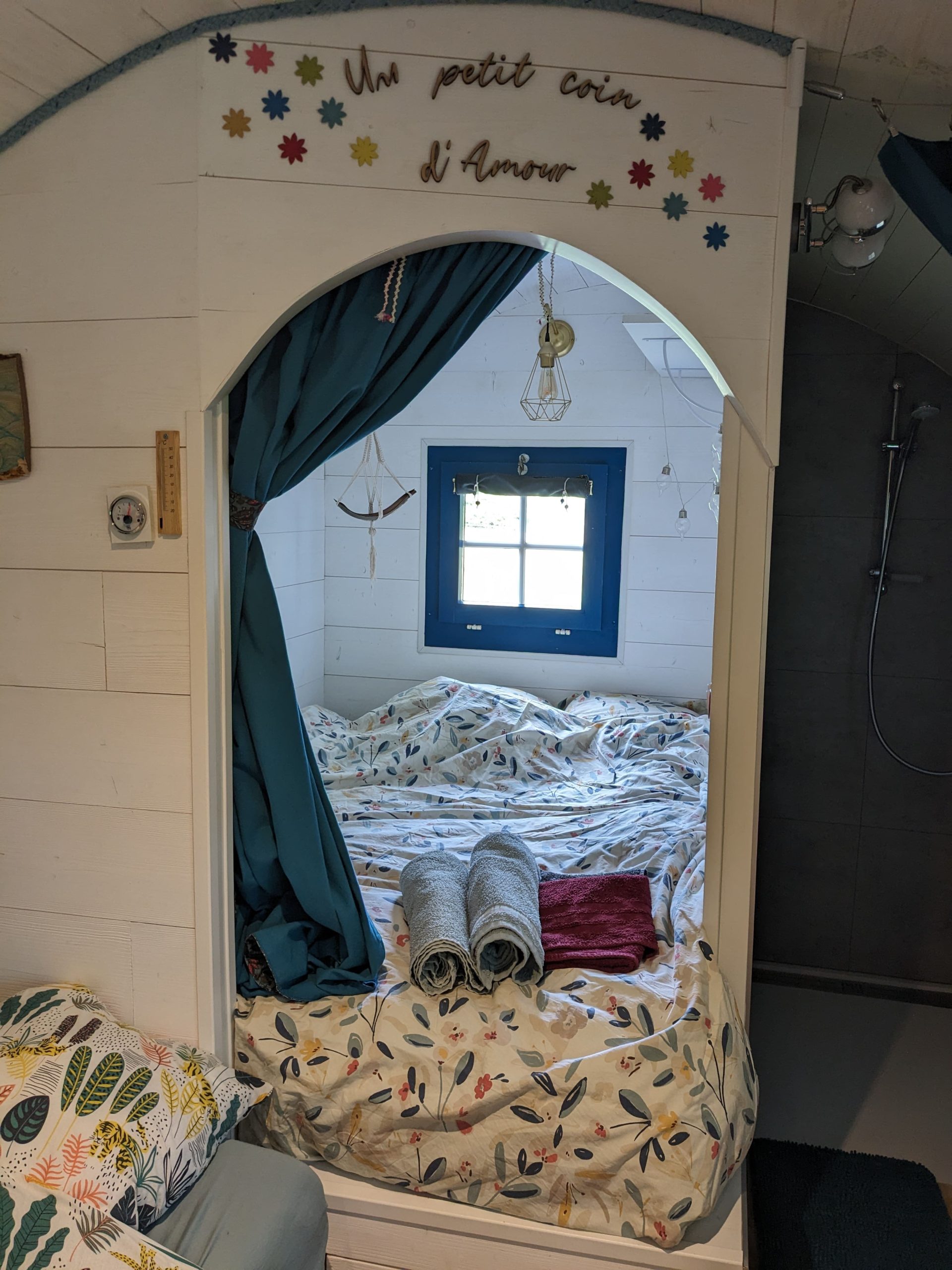 Chambre cocooning dans un hébergement romantique, décorée avec des draps fleuris.