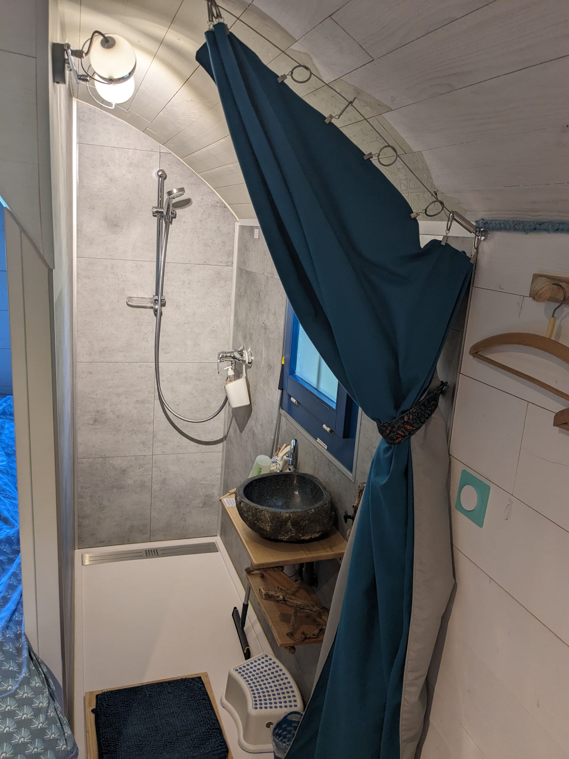 Salle de bain dun hébergement insolite avec douche moderne et décor naturel.