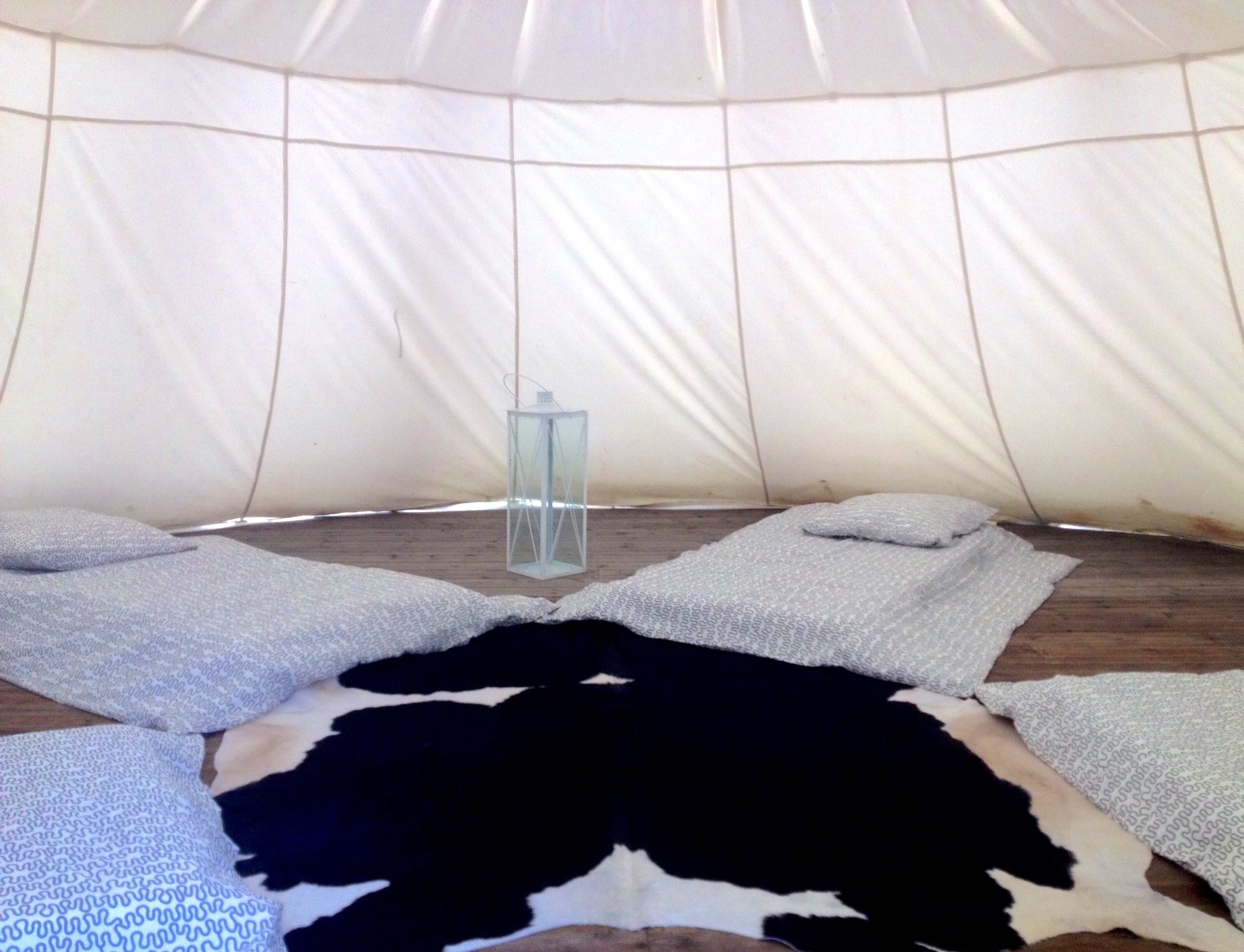 Tente de glamping spacieuse avec matelas confortables et décoration en peau de vache.
