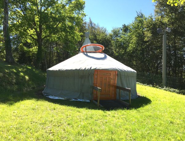 Yourte spacieuse au milieu de la nature, entourée darbres verdoyants.