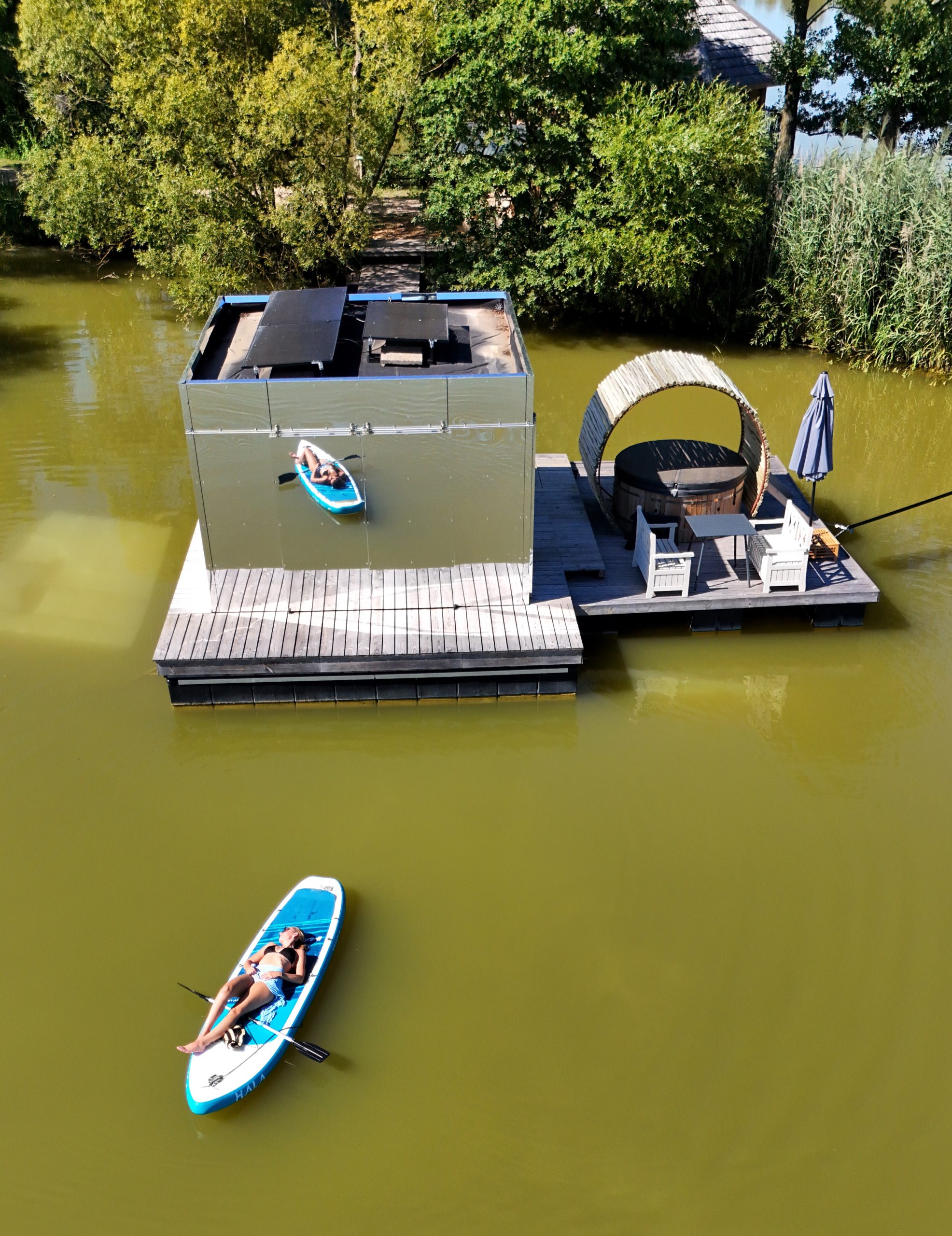 Cabane flottante moderne avec terrasse et kayak sur leau calme.