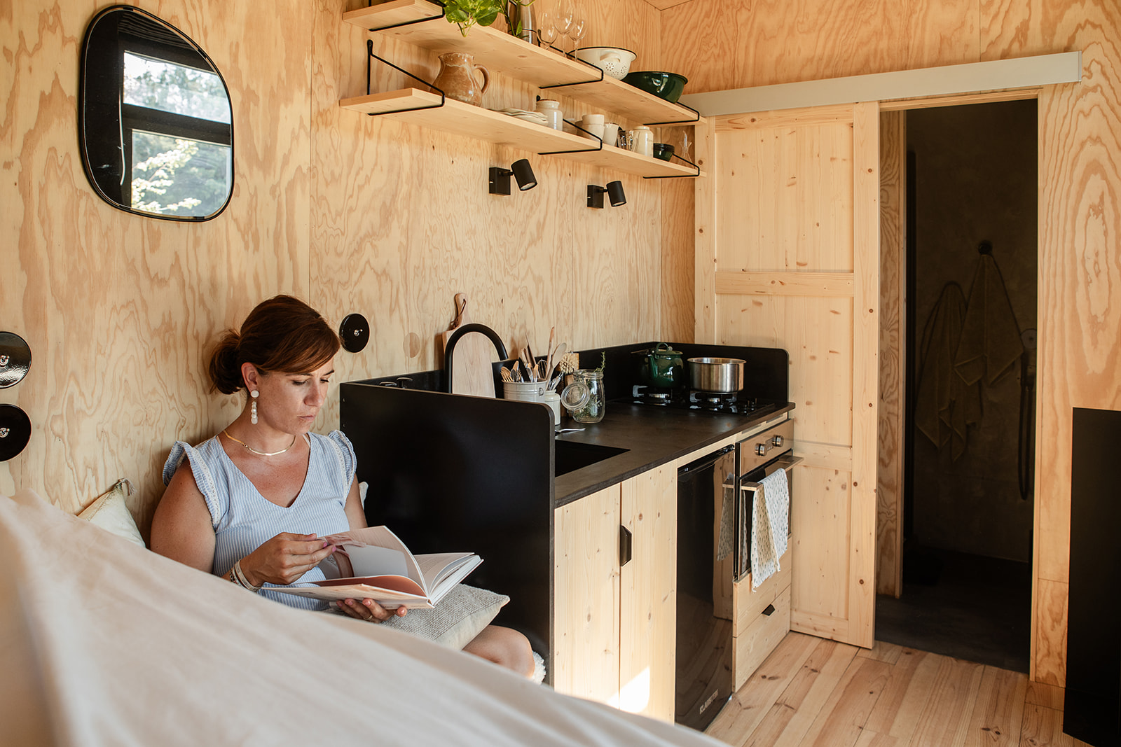 magazine-2 Tiny house en bois clair, avec cuisine équipée et coin lecture confortable.
