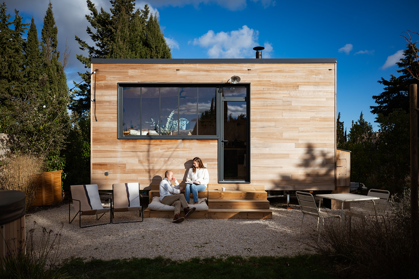 severinereynaud-photographe-TinyHouse-089-Copie1 Cabane en bois moderne avec terrasse, entourée de verdure et ciel bleu. Moment de détente en couple.