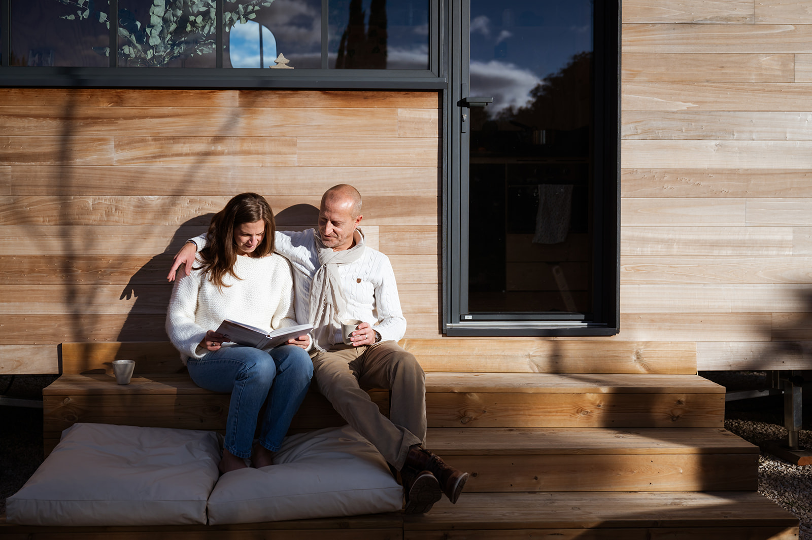 severinereynaud-photographe-TinyHouse-094-Copie1 Un chalet en bois moderne, couple détendu sur des marches, profitant du soleil.