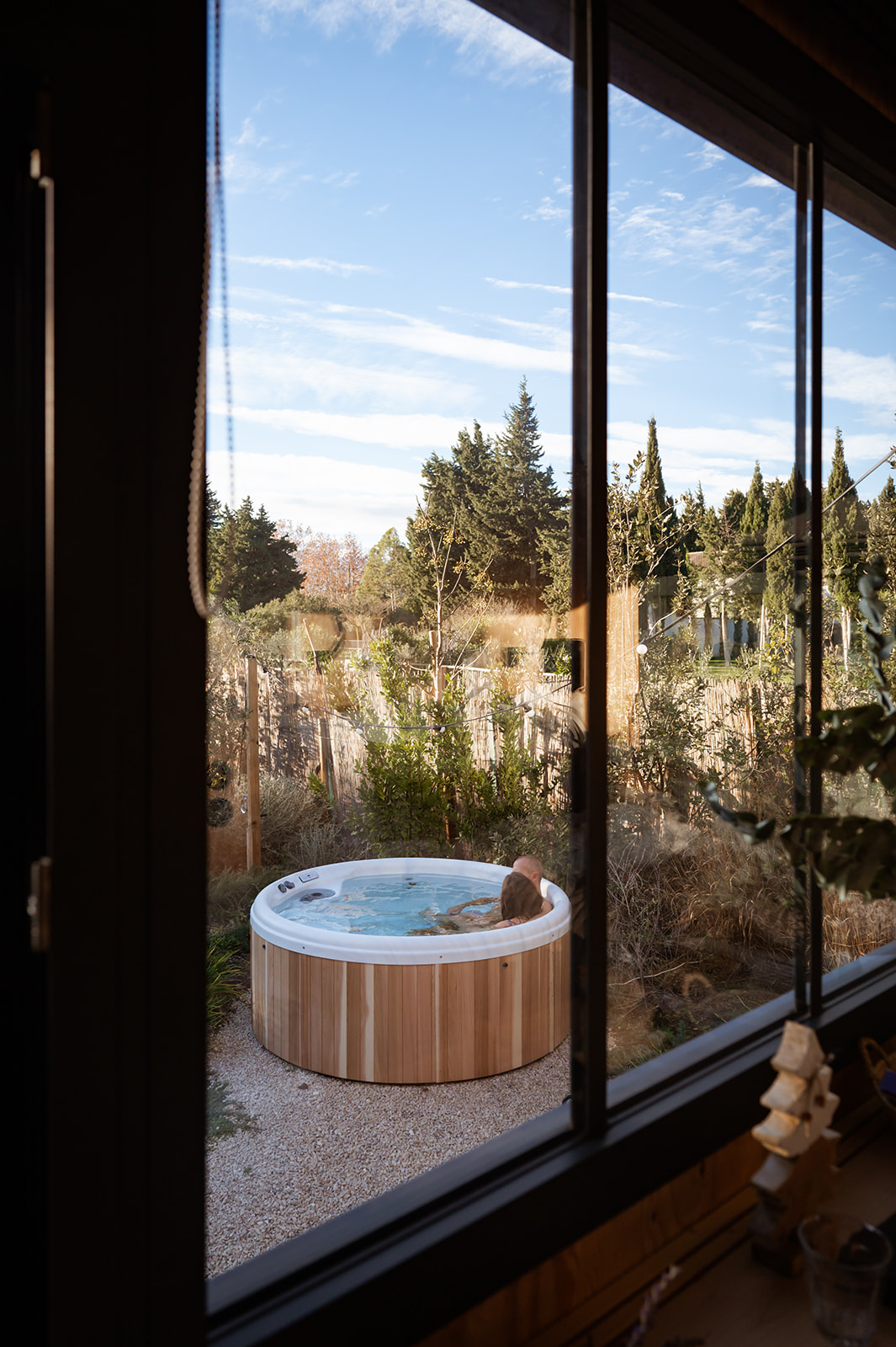 severinereynaud-photographe-TinyHouse-169-Copie1 Hébergement insolite avec jacuzzi en bois, vue sur un jardin verdoyant et ciel dégagé.
