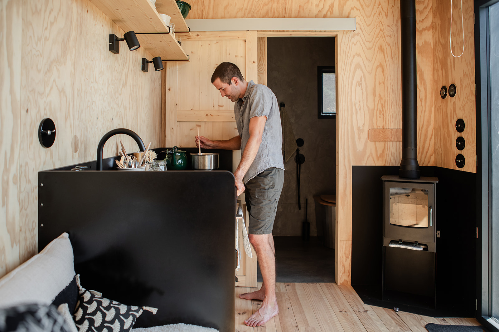 tiny-aout-126 Tiny house moderne avec intérieur en bois, cuisine fonctionnelle et poêle à bois.