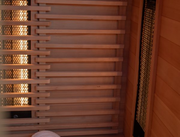 Vue rapprochée de l’intérieur d’un sauna infrarouge en bois avec une serviette roulée