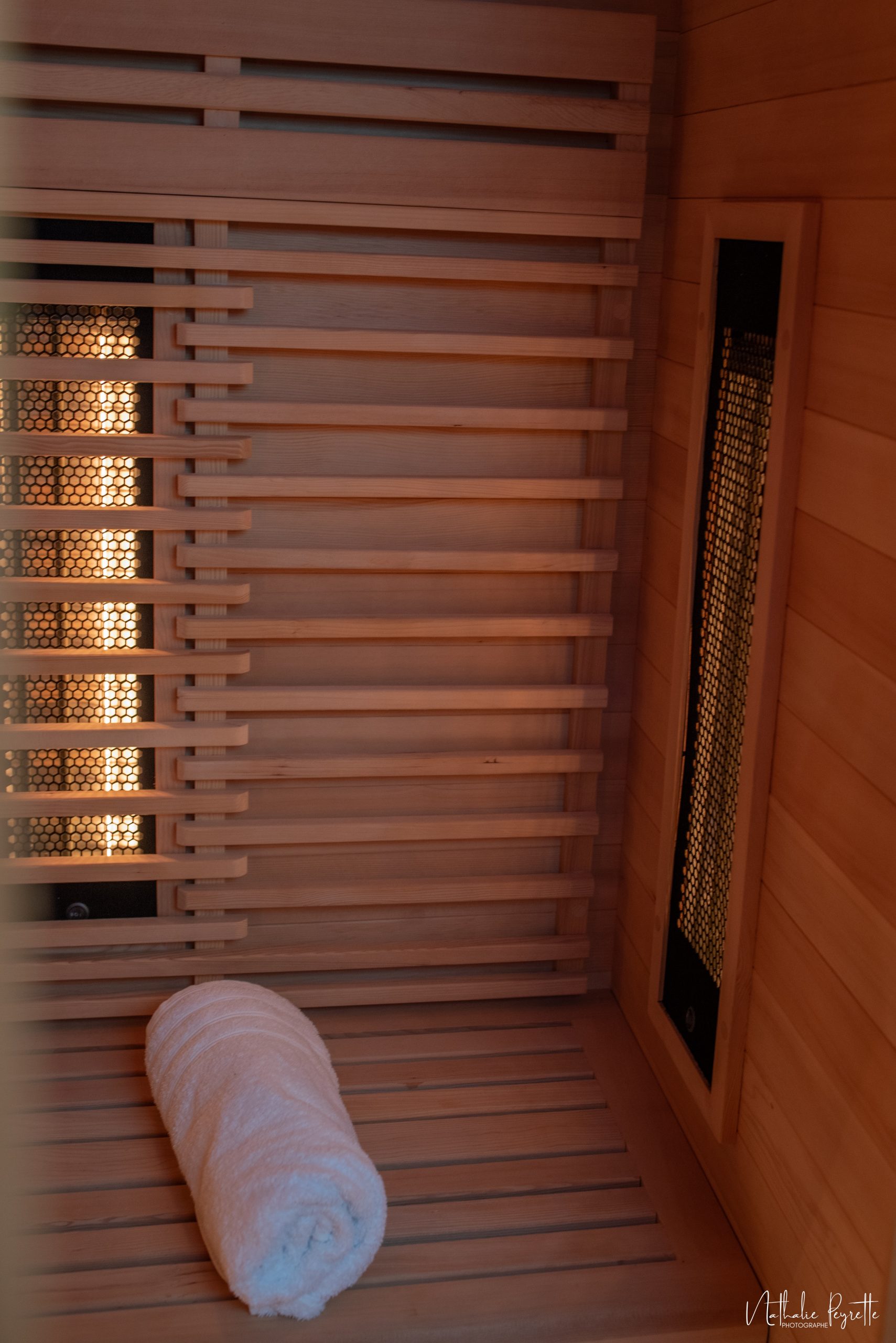 Vue rapprochée de l’intérieur d’un sauna infrarouge en bois avec une serviette roulée
